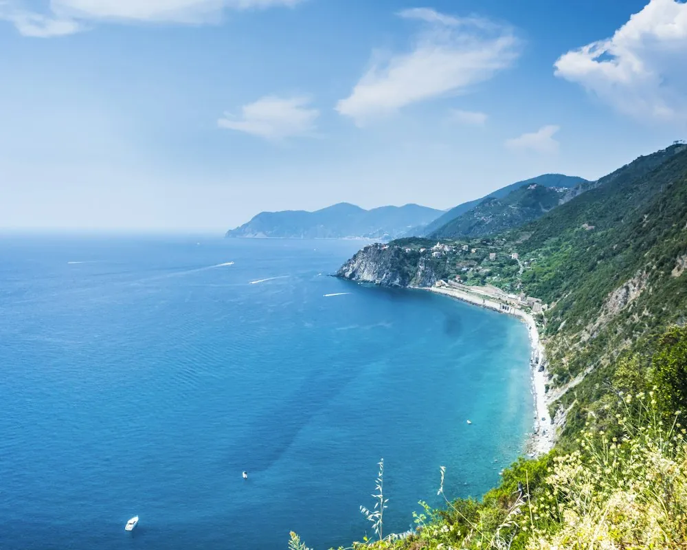 Green headland and a long curve of coast above deep blue Mediterranean water