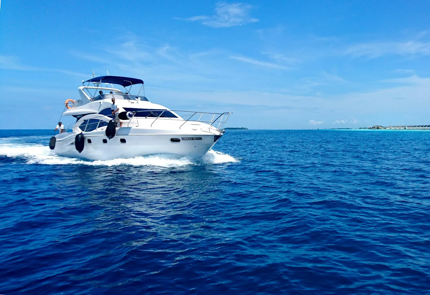 White motor yacht cruising at speed across deep blue sea