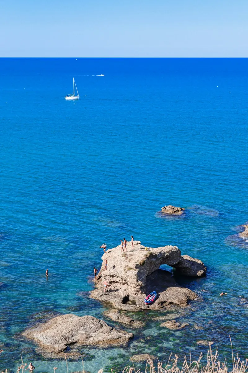 Weathered rocks rising from bright blue sea under a clear sky
